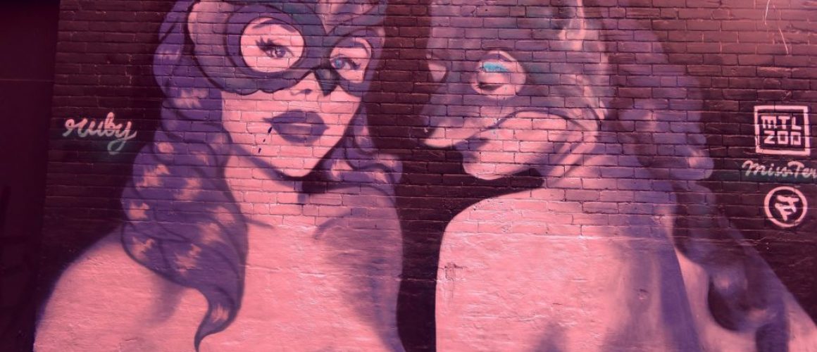 Graffiti art of two topless women wearing masks.