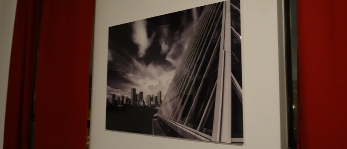 Acrylic print of clouds over buildings in black and white.