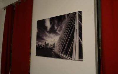 Acrylic print of clouds over buildings in black and white.