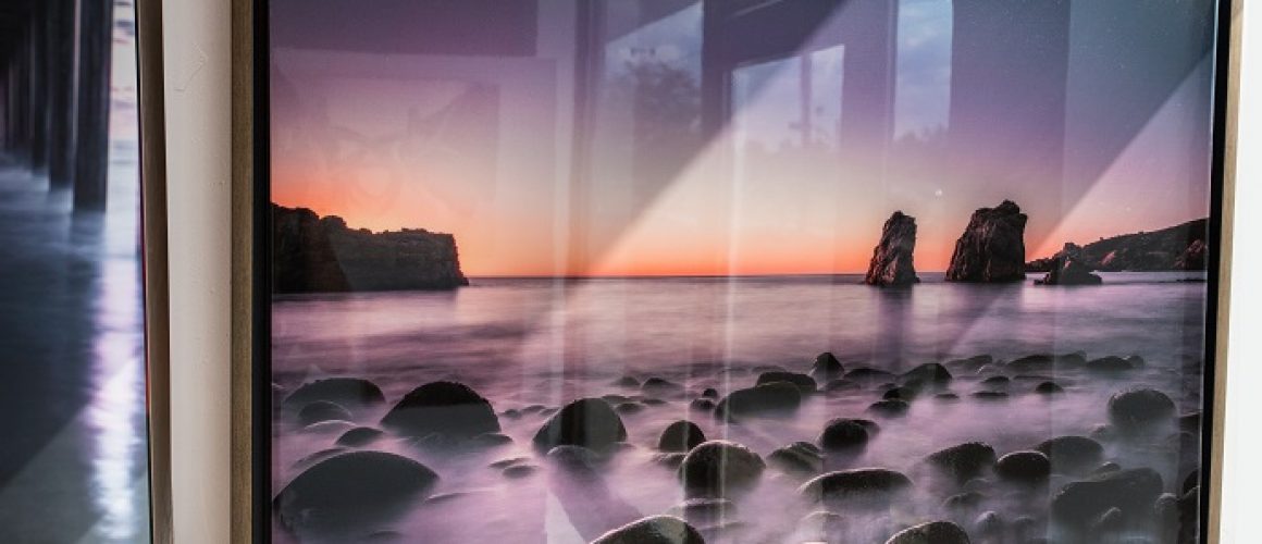 Canvas epoxy print of sunrise over ocean with rocks and fog.