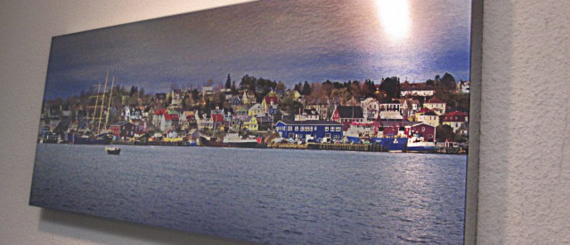 Brushed metal print of multicolored homes in front of a lake.