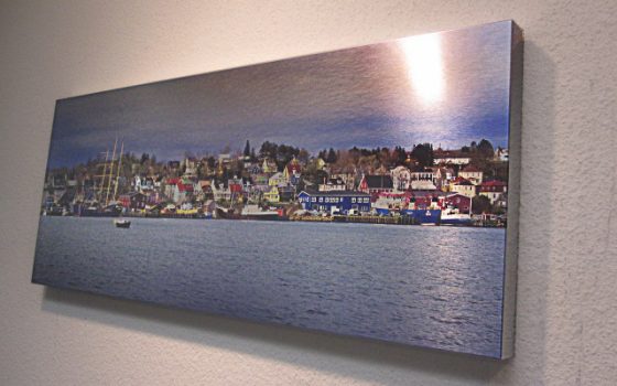 Brushed metal print of multicolored homes in front of a lake.